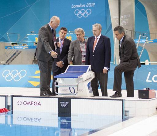 El Director de Omega Timing, Peter Hürzeler, izquierda, explica el sistema de cronometraje para los nadadores al Director del LOCOG, Sebastian Coe, segundo a la izquierda, el CEO del Swatch Group Nick Hayek, trecero a la izquierda, El International Olympic Committee President Jacques Rogge, segundo a la derecha y al Presidente de Omega Stephen Urquhart, derecha en al Aquatics Centre en el London's Olympic Park 