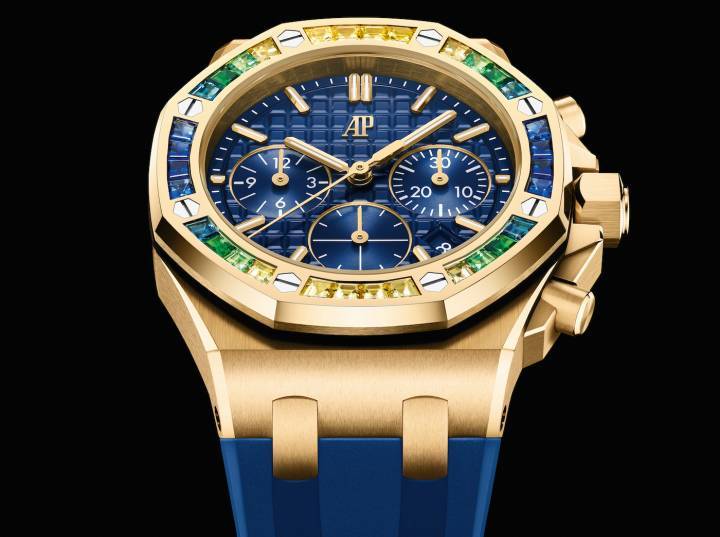 La actual línea de cronógrafos automáticos Royal Oak Offshore de 37 mm continúa el compromiso de Audemars Piguet de ofrecer deslumbrantes modelos Royal Oak Offshore para quienes tienen muñecas más pequeñas. El tema del oro amarillo y el azul se refleja en el bisel de diamantes.