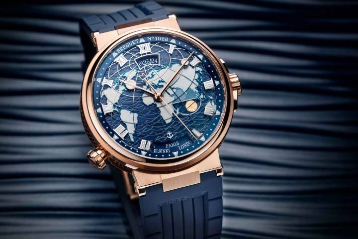 Breguet ha adaptado su complicación Hora Mundi para la colección Marine. Con un diámetro de 43,9 mm, el modelo incorpora una visualización de doble hora de cambio instantáneo con función de memoria. Esta hazaña técnica se logra a través del pulsador y la corona. Habiendo seleccionado la hora y la fecha de la primera ciudad, el propietario del reloj solo necesita configurar la segunda ciudad. A continuación, el mecanismo del reloj calcula la hora y la fecha mediante un ingenioso sistema de levas, martillos y un diferencial integrado. En ese punto, basta con presionar el pulsador para viajar de un extremo al otro del planeta, sin alterar el funcionamiento preciso del reloj. 