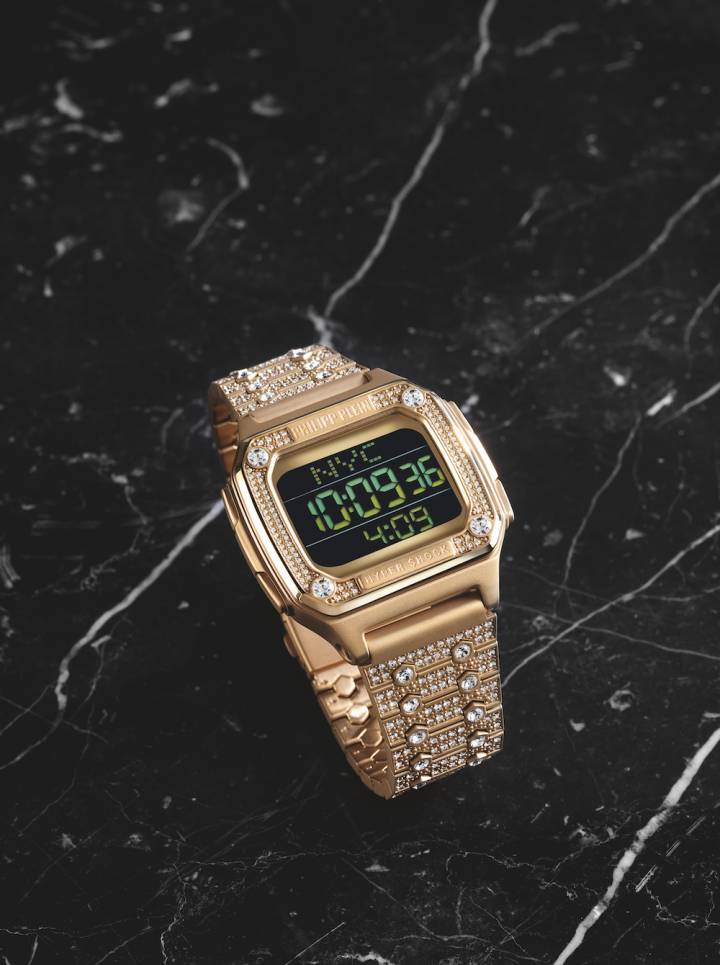 El Hyper $hock de Philipp Plein es un reloj digital disponible en oro amarillo brillante o en versiones de acero inoxidable, con un pavé de cristales blancos que cubren el anillo superior y los eslabones del brazalete.