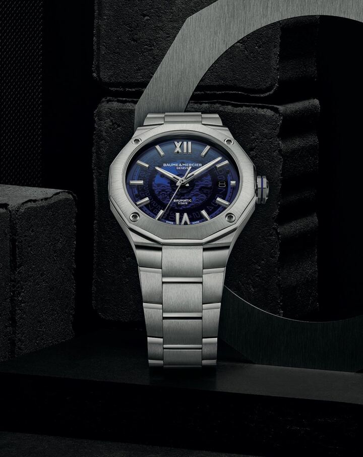 El Baumatic Riviera de 42 mm está disponible con una esfera de zafiro decorada en azul ahumado en un brazalete de acero integral, o con una esfera de zafiro decorada en gris ahumado en una correa negra flexible. La transparencia de su esfera translúcida brinda la oportunidad de admirar los trenes de engranajes en movimiento del calibre.