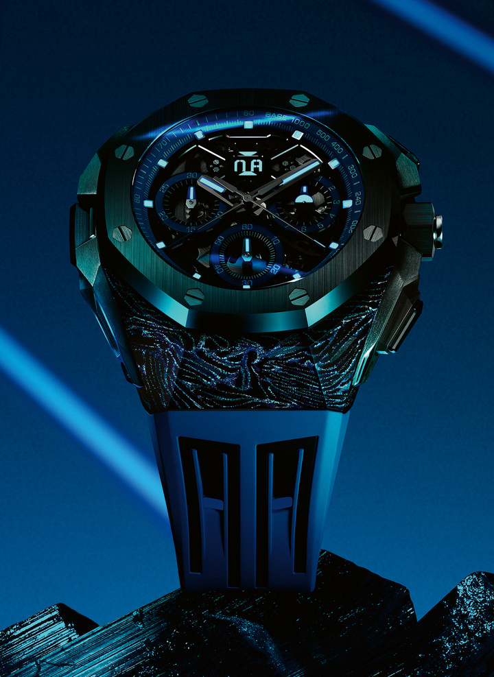 La caja ultraligera de carbono forjado de este nuevo Royal Oak Concept, que cuenta con pigmentos luminiscentes azules, se complementa con un bisel, una corona, pulsadores y un fondo de caja de cerámica negra. El reloj de dos tonos se realza con una esfera arquitectónica oscura con detalles en azul eléctrico.